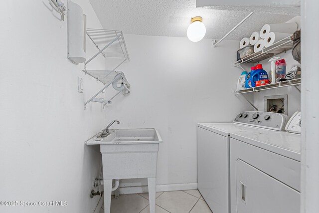 165 Escambia Ln Unit 502, Cocoa Beach, FL 32931 - laundry area featuring separate washer and dryer, light tile patterned floors, a textured ceiling, and baseboards