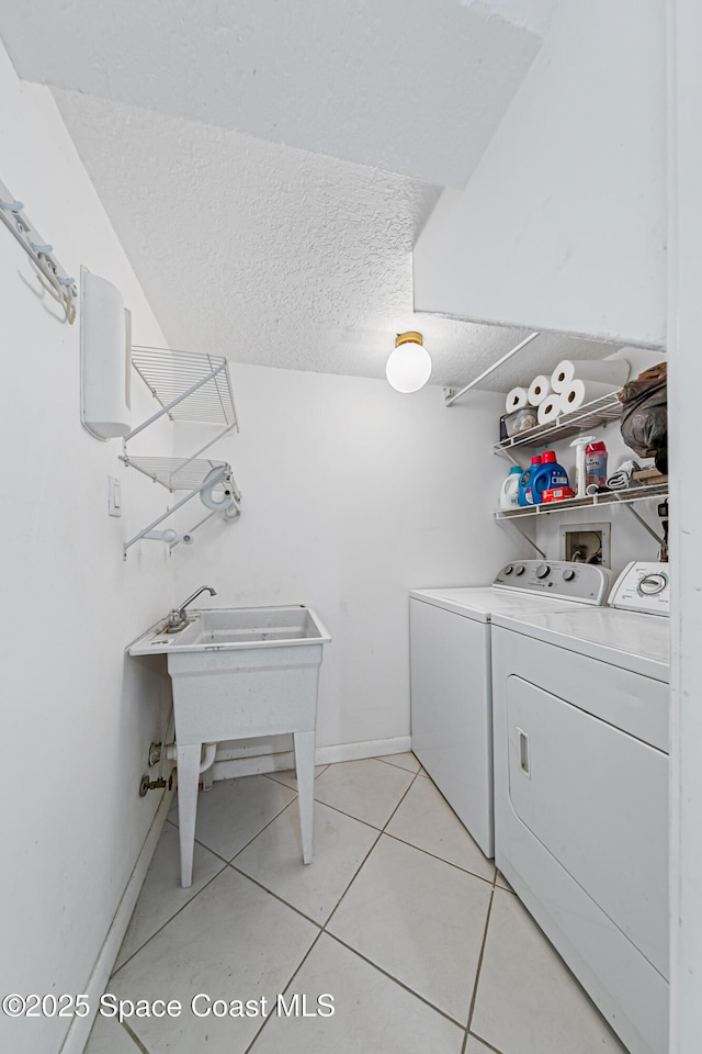 165 Escambia Ln Unit 502, Cocoa Beach, FL 32931 - washroom with washing machine and dryer, light tile patterned flooring, a textured ceiling, and baseboards