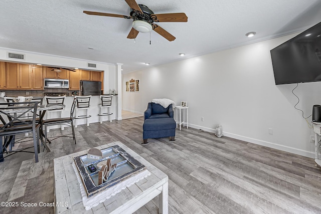 165 Escambia Ln Unit 502, Cocoa Beach, FL 32931 - living room featuring a ceiling fan, wood finished floors, a textured ceiling, baseboards, and ornamental molding