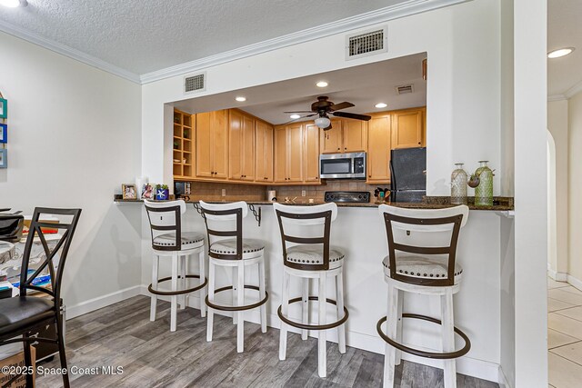 165 Escambia Ln Unit 502, Cocoa Beach, FL 32931 - kitchen featuring stainless steel microwave, crown molding, freestanding refrigerator, dark countertops, and a peninsula