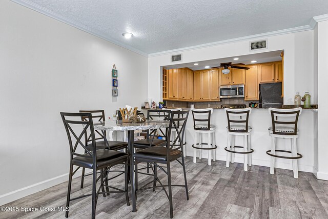 165 Escambia Ln Unit 502, Cocoa Beach, FL 32931 - dining area featuring ornamental molding, wood finished floors, a textured ceiling, ceiling fan, and baseboards