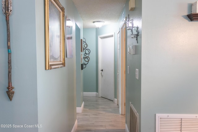 886 Spirea Dr, Rockledge, FL 32955 - hallway featuring light wood-style flooring, a textured ceiling, and baseboards