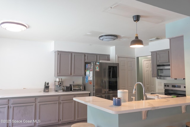 886 Spirea Dr, Rockledge, FL 32955 - kitchen featuring stainless steel appliances, gray cabinetry, a peninsula, a breakfast bar area, and pendant lighting