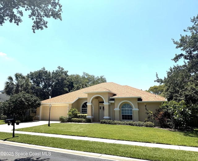 mediterranean / spanish house featuring stucco siding, a garage, a front yard, and concrete driveway