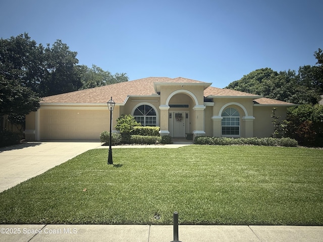 1010 Spring Oak Dr, Melbourne, FL 32901 - mediterranean / spanish house featuring an attached garage, concrete driveway, a front yard, and stucco siding
