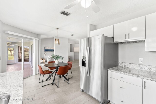 2102 Durban Ct, Rockledge, FL 32955 - kitchen featuring stainless steel refrigerator with ice dispenser, a ceiling fan, white cabinetry, pendant lighting, and light stone countertops
