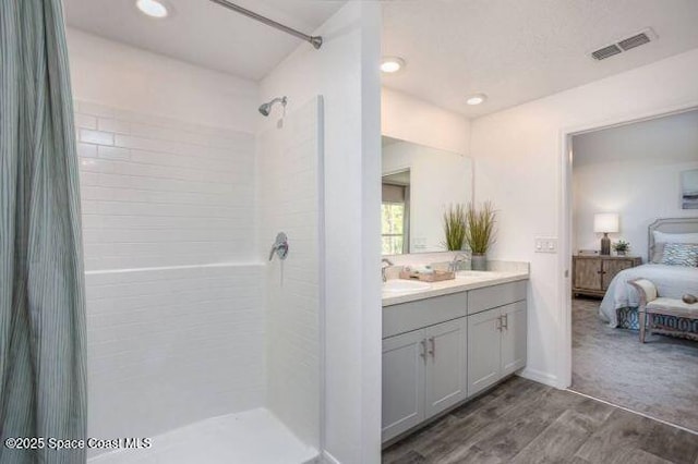bathroom with ensuite bath, a tile shower, wood finished floors, vanity, and recessed lighting