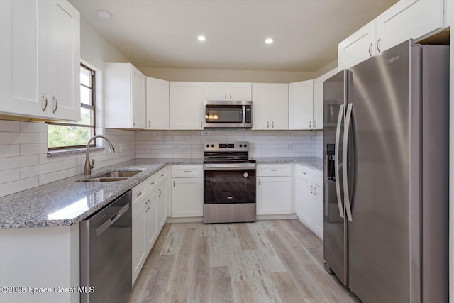 129 Irvine Ave SE, Palm Bay, FL 32909 - kitchen with appliances with stainless steel finishes, a sink, light wood finished floors, white cabinetry, and recessed lighting