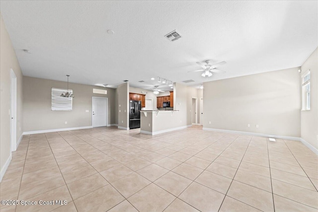 unfurnished living room with light tile patterned flooring, a ceiling fan, a textured ceiling, and baseboards