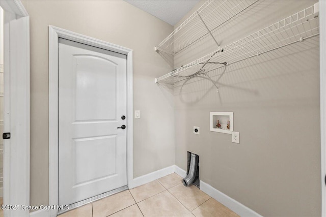 clothes washing area featuring electric dryer hookup, washer hookup, light tile patterned flooring, and baseboards