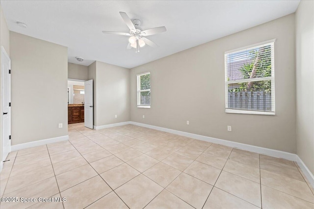 unfurnished room with healthy amount of natural light, light tile patterned floors, ceiling fan, and baseboards