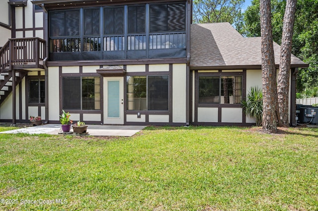 747 Greenwood Manor Cir Unit 17-A, West Melbourne, FL 32904 - rear view of property featuring stucco siding, roof with shingles, a yard, and stairway