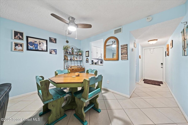 dining room with a textured ceiling, ceiling fan, light tile patterned floors, and baseboards