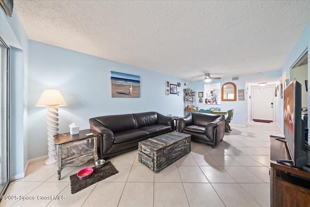 tiled living room with ceiling fan, a textured ceiling, and baseboards