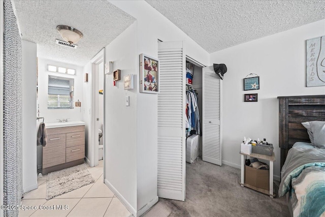 bedroom with a textured ceiling, a sink, a closet, baseboards, and connected bathroom