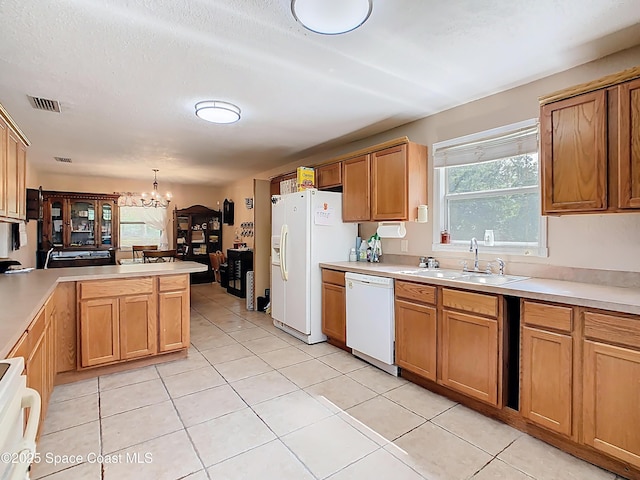 4432 Freedom Rd, Kissimmee, FL 34746 - kitchen with a sink, white appliances, a chandelier, a peninsula, and light tile patterned floors