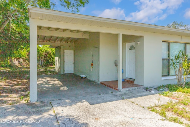 1049 Azalea Ln, Cocoa, FL 32922 - doorway to property featuring stucco siding, driveway, and an attached carport