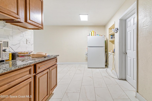 1049 Azalea Ln, Cocoa, FL 32922 - kitchen with freestanding refrigerator, light marble finish flooring, decorative backsplash, stone countertops, and brown cabinets