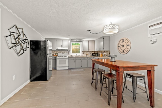 kitchen with gas range gas stove, freestanding refrigerator, gray cabinetry, light countertops, and backsplash