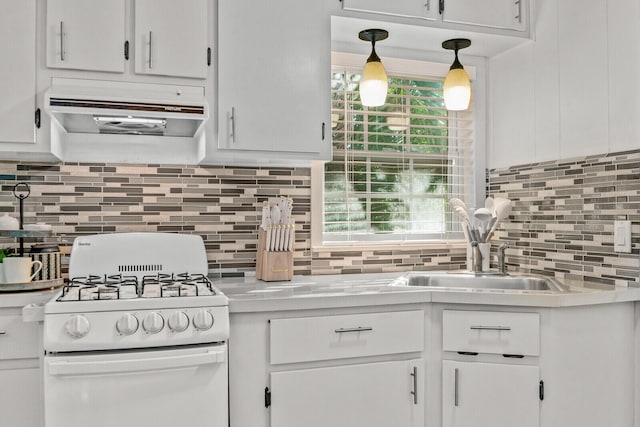 kitchen featuring white gas range, under cabinet range hood, light countertops, and decorative backsplash
