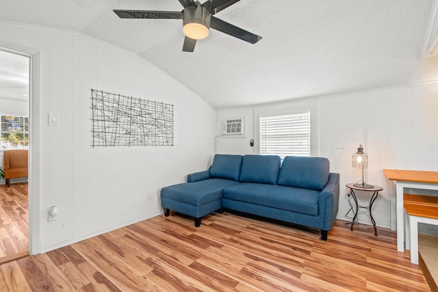 living area featuring lofted ceiling, light wood-style flooring, ceiling fan, ornamental molding, and a textured ceiling