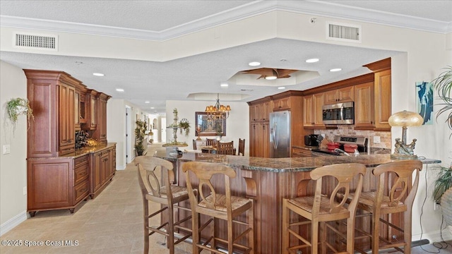 480 Sail Ln Unit 607, Merritt Island, FL 32953 - kitchen with stainless steel appliances, tasteful backsplash, brown cabinets, a peninsula, and dark stone counters
