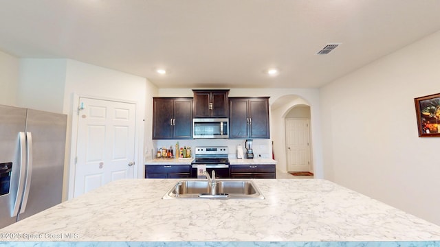 1491 Higbee St SE, Palm Bay, FL 32909 - kitchen featuring appliances with stainless steel finishes, a sink, a center island with sink, light countertops, and arched walkways