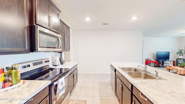 1491 Higbee St SE, Palm Bay, FL 32909 - kitchen with stainless steel appliances, a sink, dark brown cabinetry, light tile patterned floors, and open floor plan