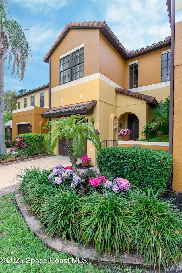 view of front of property with a tile roof, stucco siding, a garage, and concrete driveway