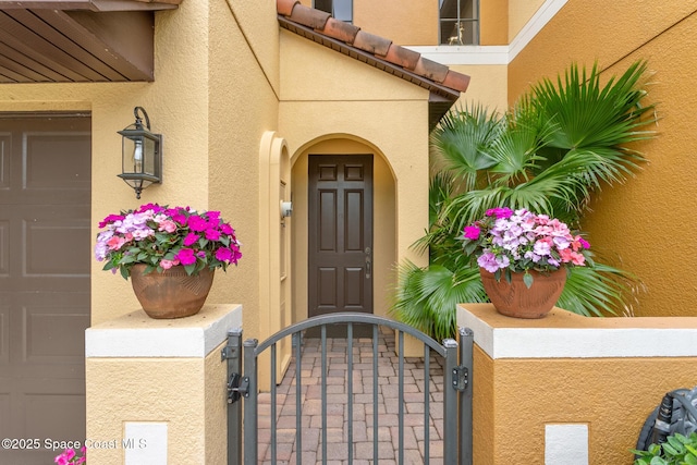 property entrance featuring a gate, stucco siding, and fence