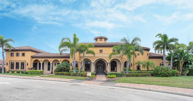 view of front facade featuring a tiled roof, stucco siding, and a front lawn