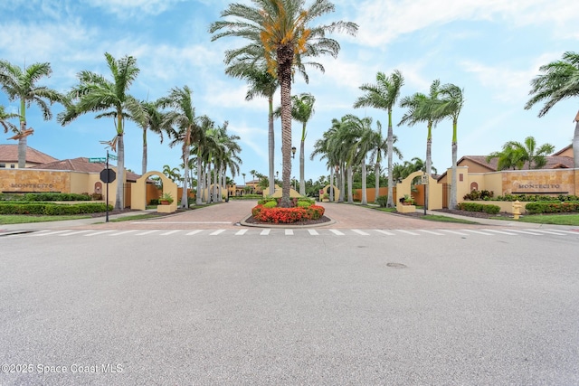 view of asphalt street with a residential view, curbs, sidewalks, traffic signs, and a gate