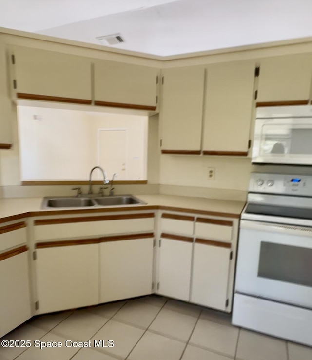 kitchen featuring white appliances, a sink, light countertops, and light tile patterned floors