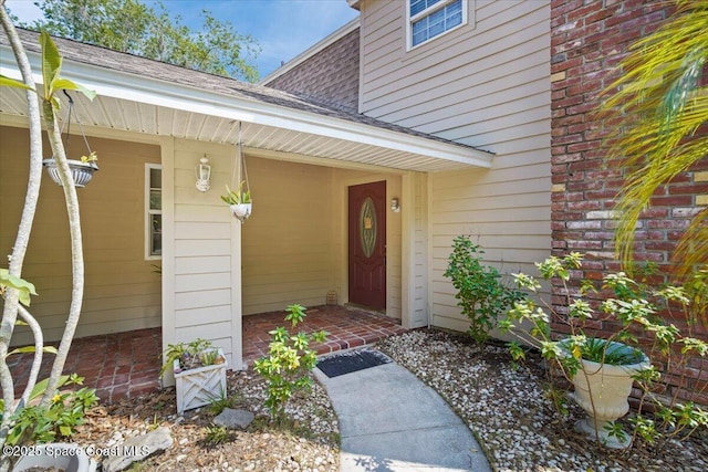 965 Bluegrass Ln, Rockledge, FL 32955 - view of exterior entry featuring brick siding, a shingled roof, and covered porch