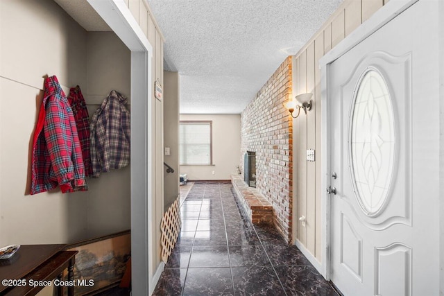 965 Bluegrass Ln, Rockledge, FL 32955 - foyer entrance featuring a textured ceiling, brick wall, a fireplace, dark marble finish floors, and baseboards