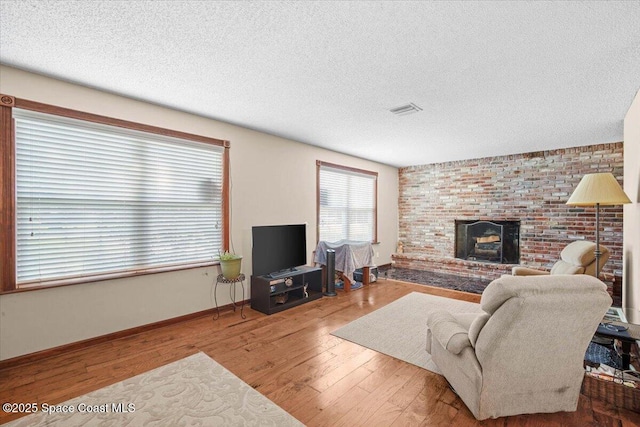 965 Bluegrass Ln, Rockledge, FL 32955 - living area with wood finished floors, a brick fireplace, baseboards, and a textured ceiling