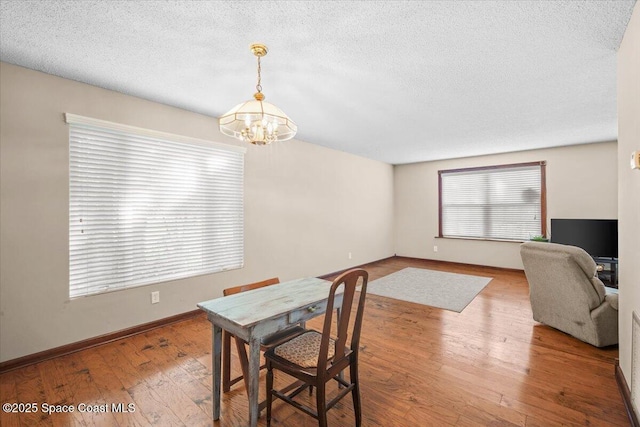 965 Bluegrass Ln, Rockledge, FL 32955 - dining area featuring a chandelier, a textured ceiling, wood-type flooring, and baseboards
