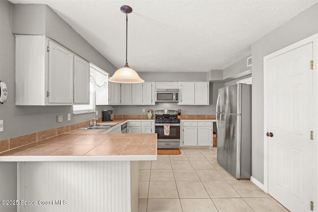 965 Bluegrass Ln, Rockledge, FL 32955 - kitchen featuring appliances with stainless steel finishes, a peninsula, a sink, light tile patterned floors, and decorative light fixtures