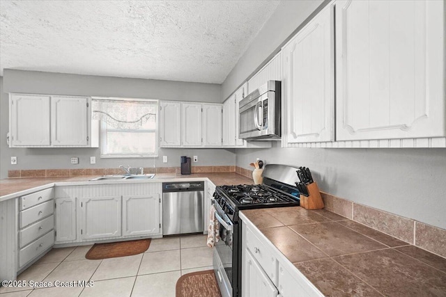 965 Bluegrass Ln, Rockledge, FL 32955 - kitchen featuring stainless steel appliances, a sink, a textured ceiling, white cabinetry, and light tile patterned floors
