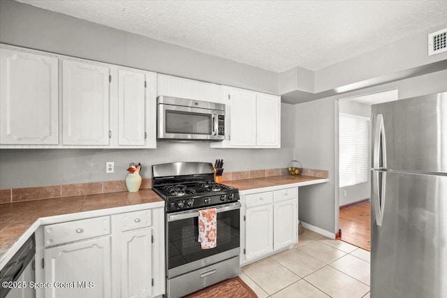 965 Bluegrass Ln, Rockledge, FL 32955 - kitchen featuring appliances with stainless steel finishes, white cabinetry, light tile patterned flooring, and a textured ceiling