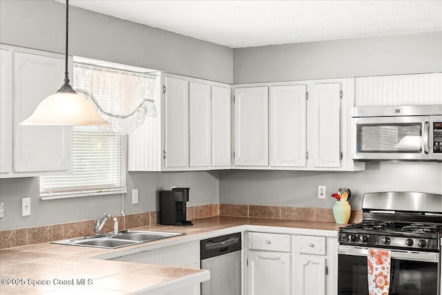 965 Bluegrass Ln, Rockledge, FL 32955 - kitchen with stainless steel appliances, white cabinets, a sink, and decorative light fixtures