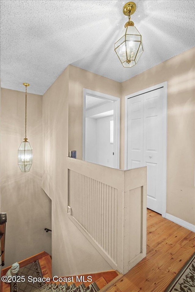 965 Bluegrass Ln, Rockledge, FL 32955 - hallway featuring baseboards, wood finished floors, a textured ceiling, and a chandelier