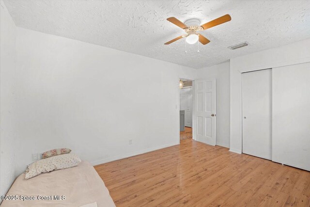 965 Bluegrass Ln, Rockledge, FL 32955 - unfurnished bedroom with wood finished floors, a textured ceiling, a closet, ceiling fan, and baseboards