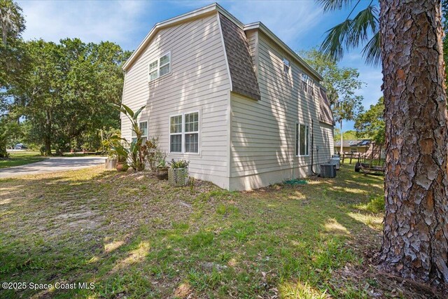 965 Bluegrass Ln, Rockledge, FL 32955 - view of property exterior featuring central AC, a yard, and roof with shingles