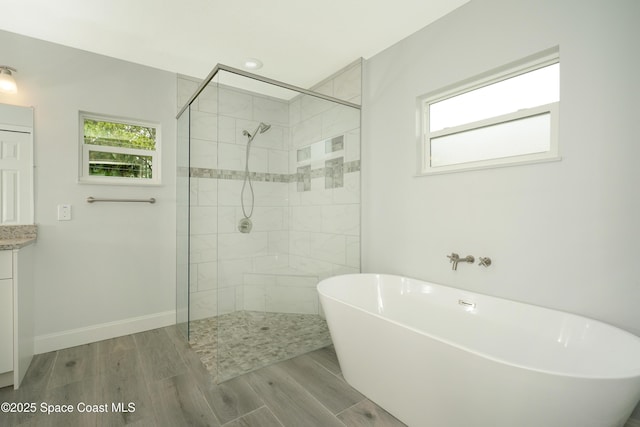 766 Tooley Rd SW, Palm Bay, FL 32908 - bathroom featuring a soaking tub, a tile shower, wood finished floors, vanity, and baseboards