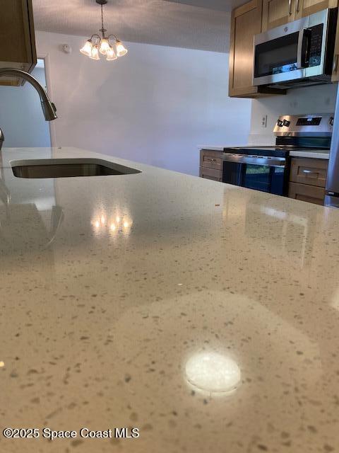 240 Perth Ave, Merritt Island, FL 32953 - kitchen with appliances with stainless steel finishes, a sink, light stone countertops, and a chandelier