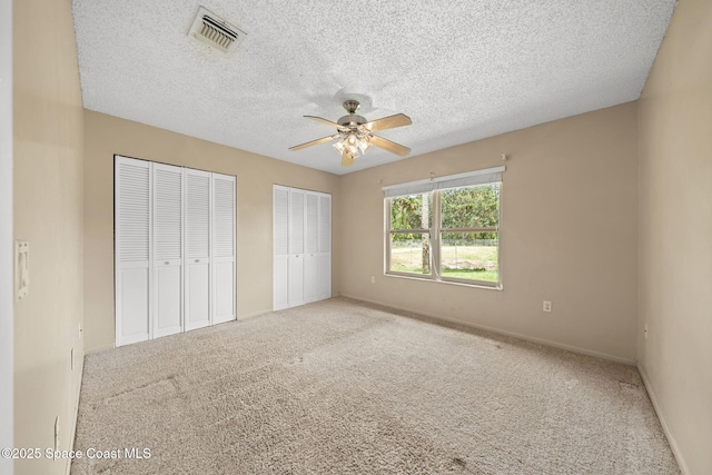 1401 Ruffin Cir SE, Palm Bay, FL 32909 - unfurnished bedroom featuring two closets, carpet flooring, baseboards, a textured ceiling, and ceiling fan