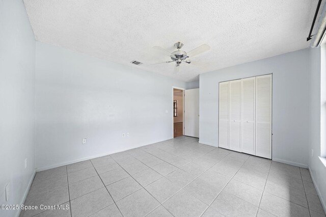 1401 Ruffin Cir SE, Palm Bay, FL 32909 - unfurnished bedroom with a closet, a textured ceiling, light tile patterned floors, and a ceiling fan