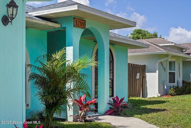 1709 Palm Ridge Rd, Melbourne, FL 32935 - doorway to property with stucco siding, a shingled roof, and a yard