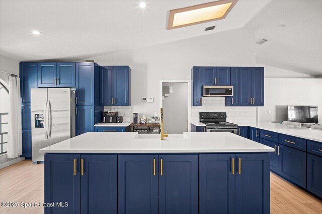 1709 Palm Ridge Rd, Melbourne, FL 32935 - kitchen with stainless steel appliances, blue cabinets, a sink, light countertops, and decorative backsplash